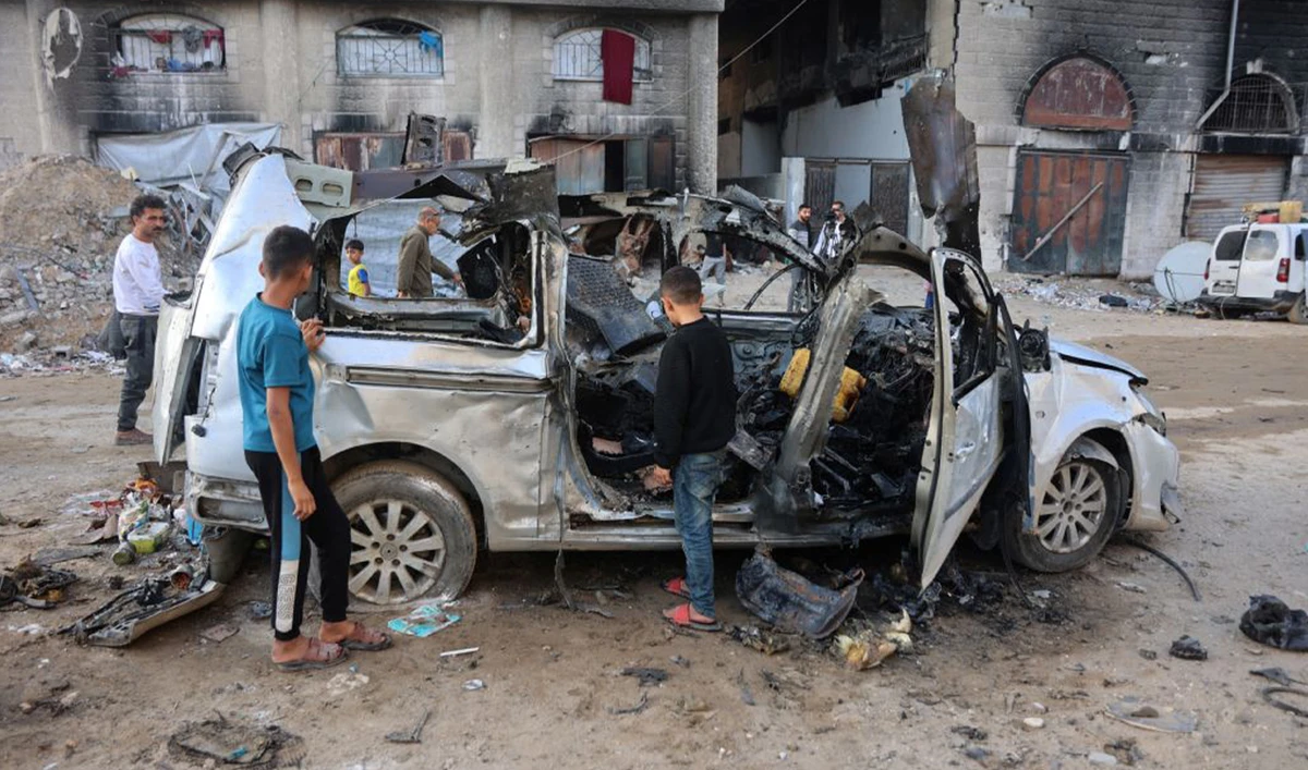 Palestinian boys inspect what remains of a destroyed vehicle targeted by the Israeli military, in Gaza City, on November 22, 2025. (AFP)
