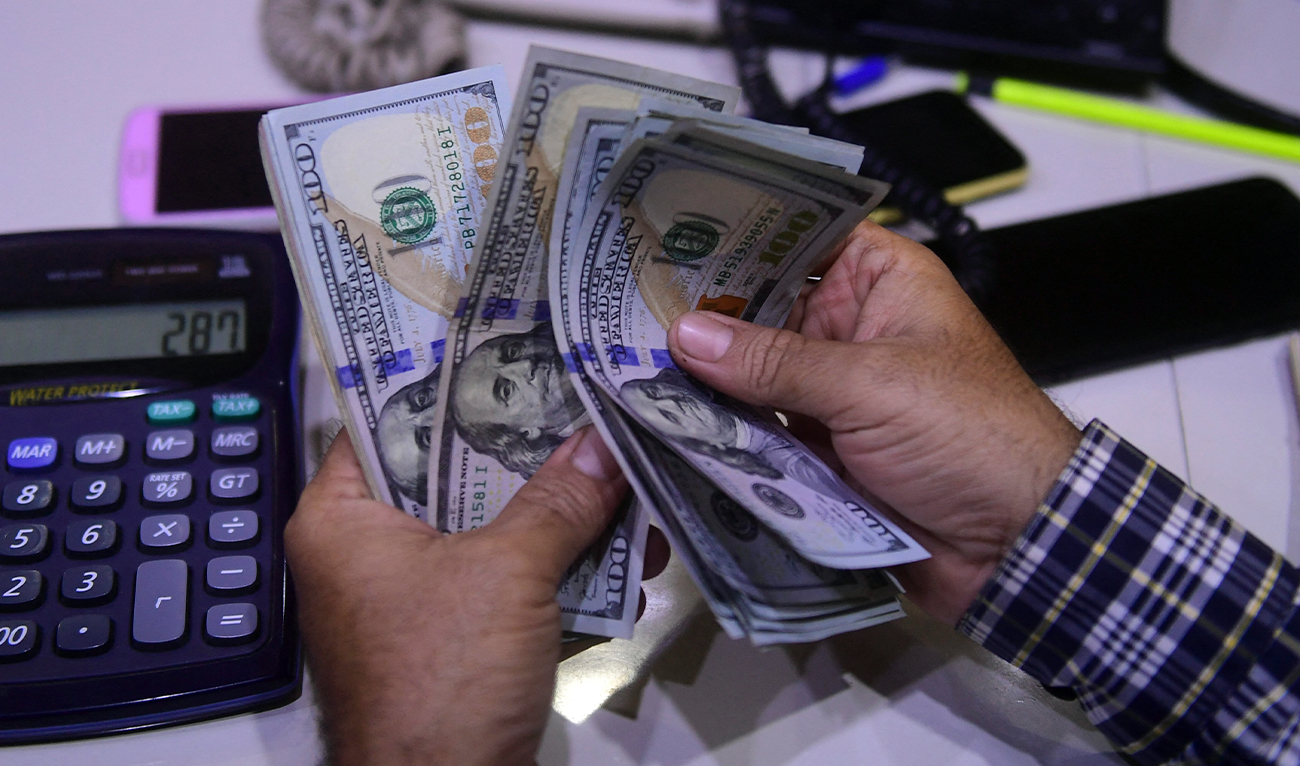 A dealer counts US dollars at a money exchange market in Karachi, Pakistan, on March 2, 2023. ( AFP/File)