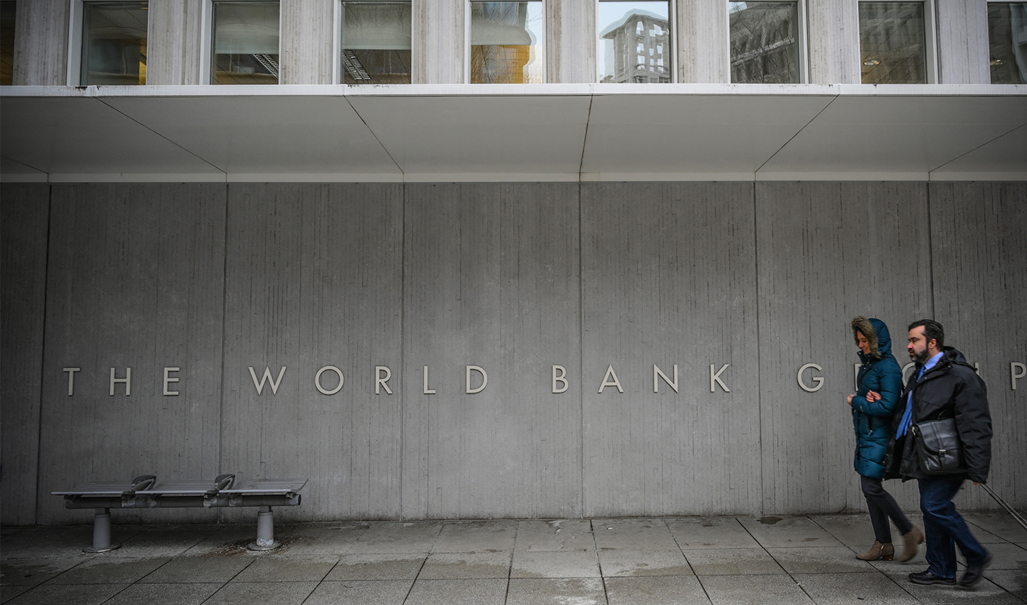 Two perosns walk by the building of the Washington-based global development lender, The World Bank Group, in Washington on January 17, 2019. (AFP/File)