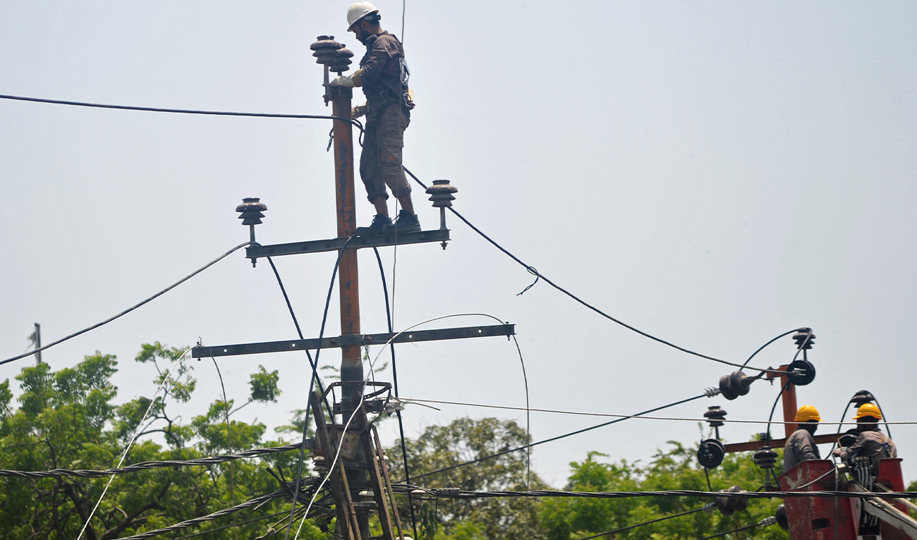 Men work on electric pylons along the roadside in Karachi on May 30, 2021. (AFP/File)