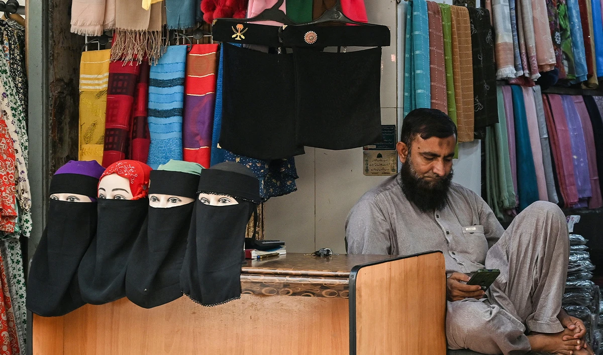 A shopkeeper selling niqab or face veils waits for customers at a market in Karachi on November 24, 2025. (AFP/File)