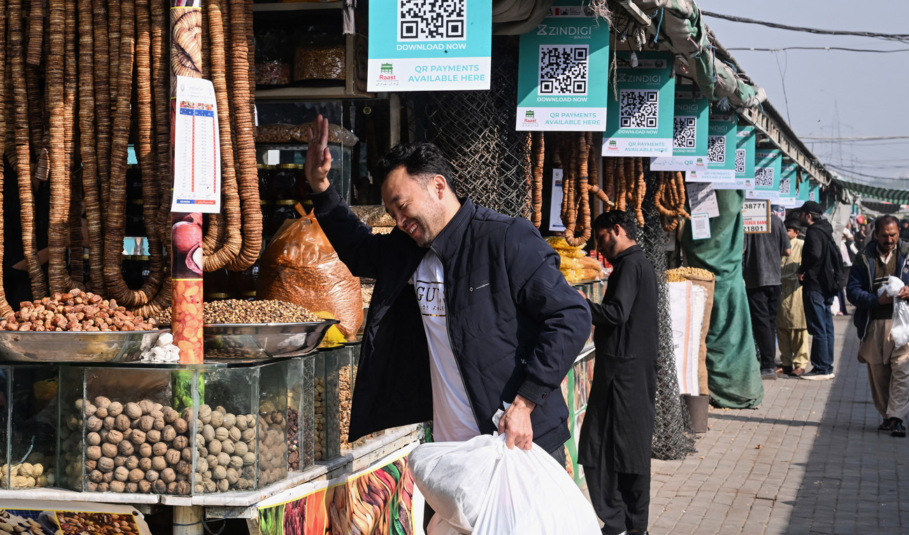 A customer reacts as digital cashless payment QR (quick response) codes are displayed at a market in Islamabad on November 25, 2025. (AFP/File)