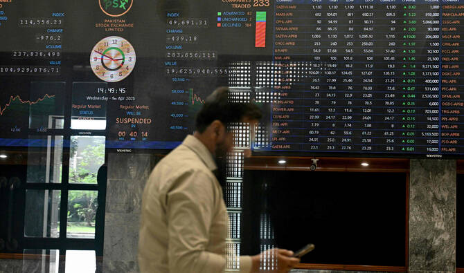 A stockbroker walks past share prices on a financial market board during a trading session at the Pakistan Stock Exchange (PSX) in Karachi on April 9, 2025. (AFP/File)