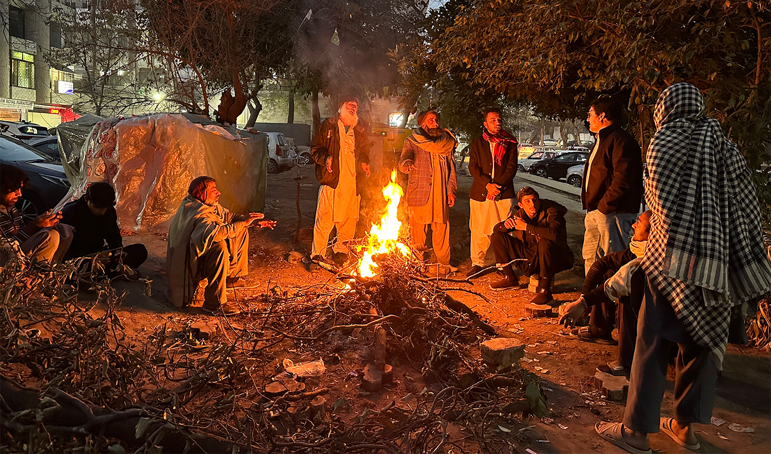 Daily wage workers sit around a fire along a roadside in Islamabad on January 23, 2026. (AN Photo)