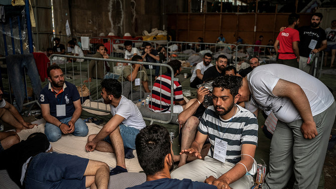 In this file photo, taken on June 15, 2023, migrants who were rescued at sea off Greece, along with other migrants, after their boat capsized, are seen inside a warehouse, used as shelter, at the port of Kalamata, Greece. (REUTERS/File)
