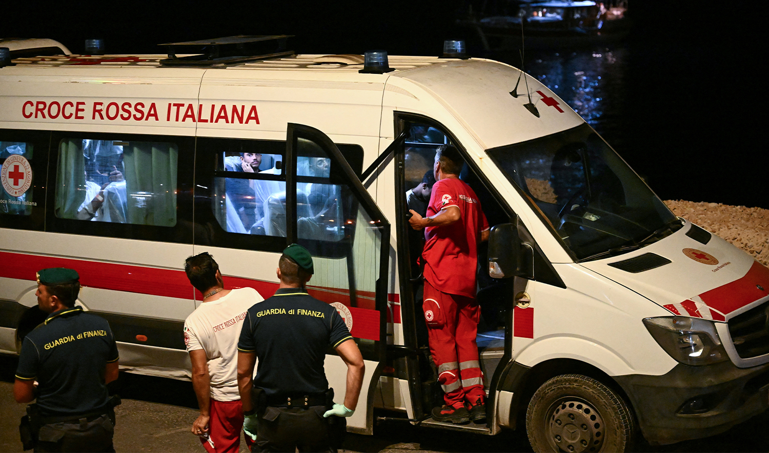 Migrants sit in a Red Cross vehicle after disembarking on Lampedusa after being rescued from their boat that sank in the Mediterranean Sea off the Italian island of Lampedusa on August 14, 2025. (AFP/File)