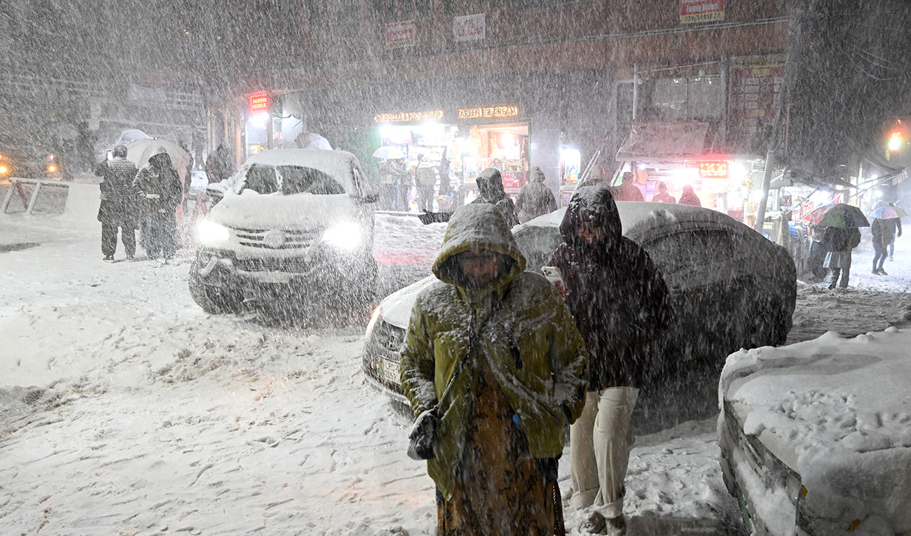 Tourists walk along a road as it snows in Murree, some 60km north of Islamabad, Pakistan, on January 23, 2026. (AFP/File)