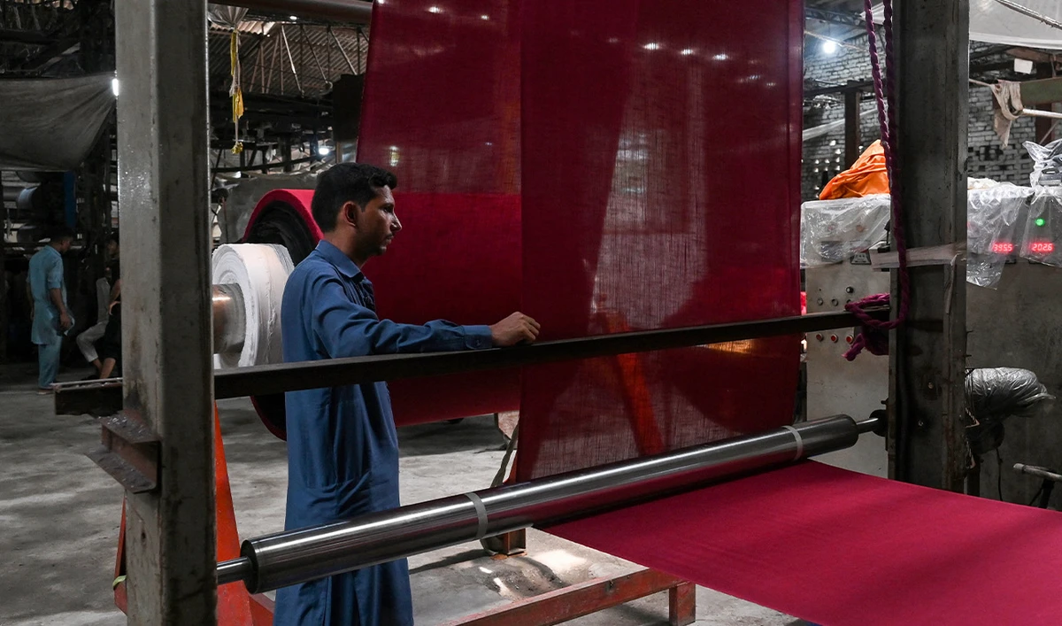 A factory worker monitors fabric during the dyeing process on the outskirts of Lahore on July 7, 2025. (AFP/File)
