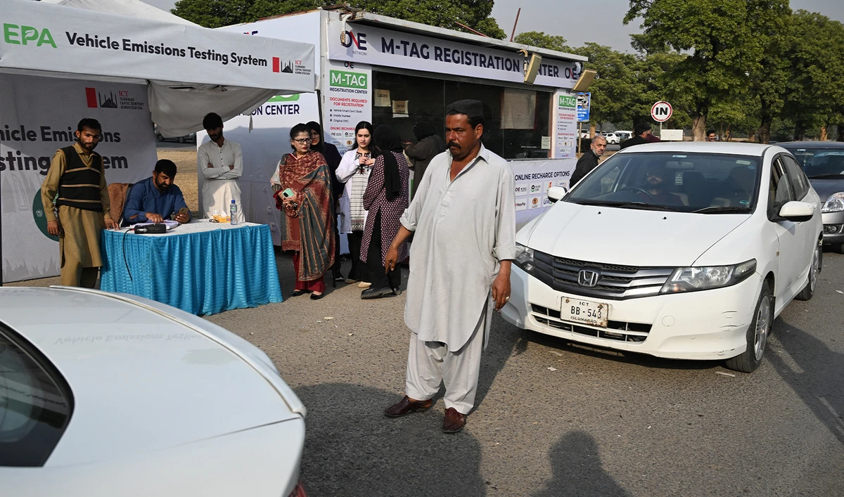 This picture taken on December 10, 2025, shows residents examining their cars at an emission testing point in Islamabad. (AFP/File)