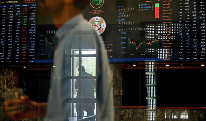 A stockbroker walks past share prices on a financial market board during a trading session at the Pakistan Stock Exchange (PSX) in Karachi on April 9, 2025. (AFP/File)