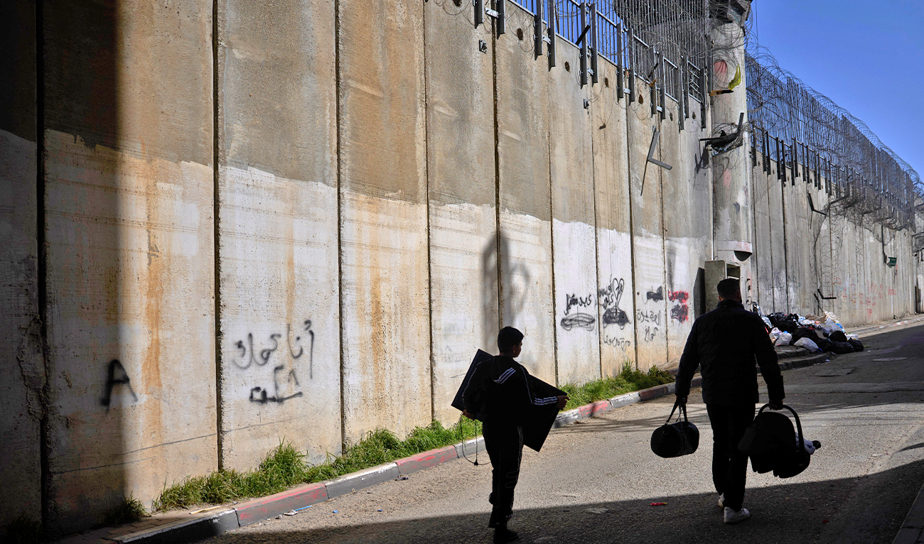 Palestinians walk along the separation barrier between the West Bank and east Jerusalem neighborhood of Beit Hanina, on Feb. 15, 2026. (AP)