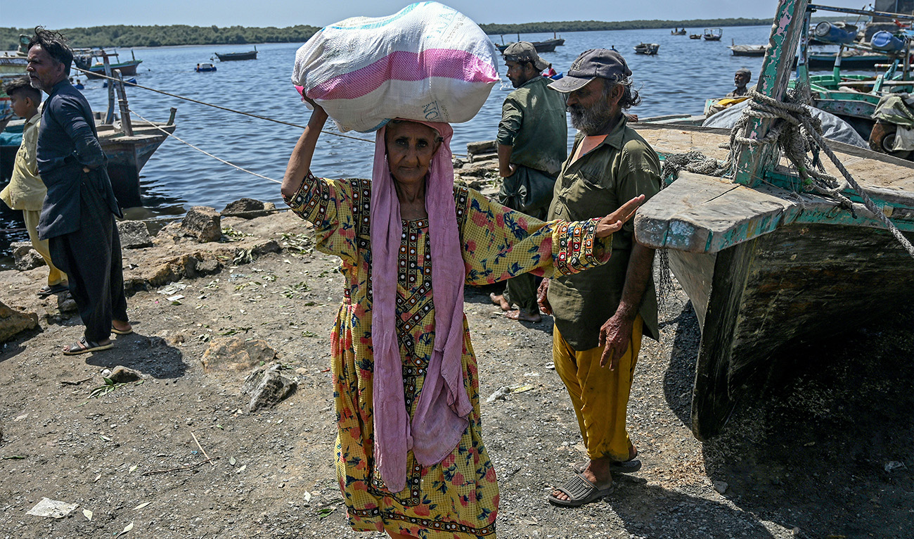 An old woman carries a ration kit distributed by the DUA Foundation, a non-governmental welfare organisation, during the Islamic holy fasting month of Ramadan, in Karachi on March 22, 2025. (AFP/File)