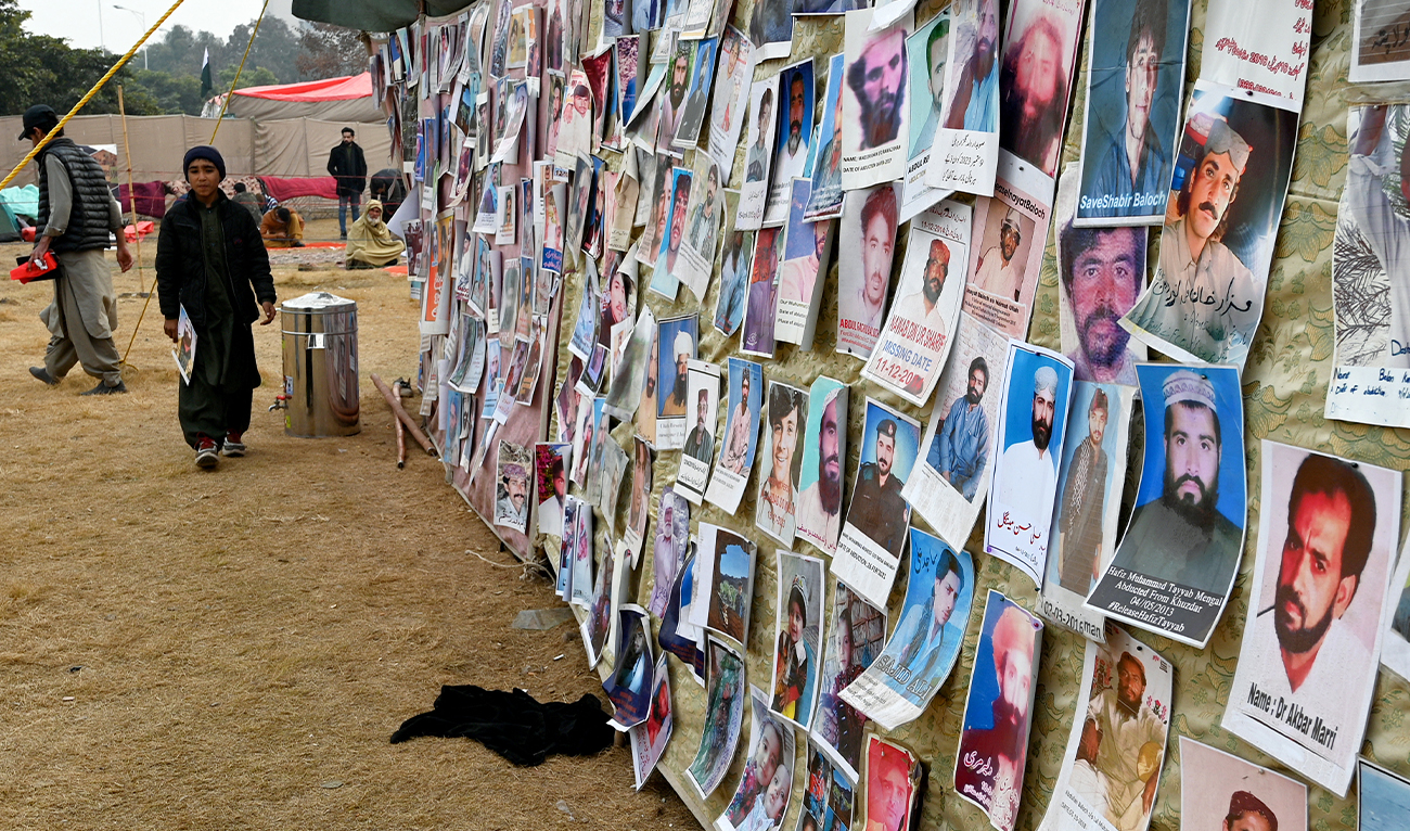 A boy walks past photographs of missing persons from southwestern Balochistan province, displayed during a demonstration in Islamabad on January 22, 2024. (AFP/ file)