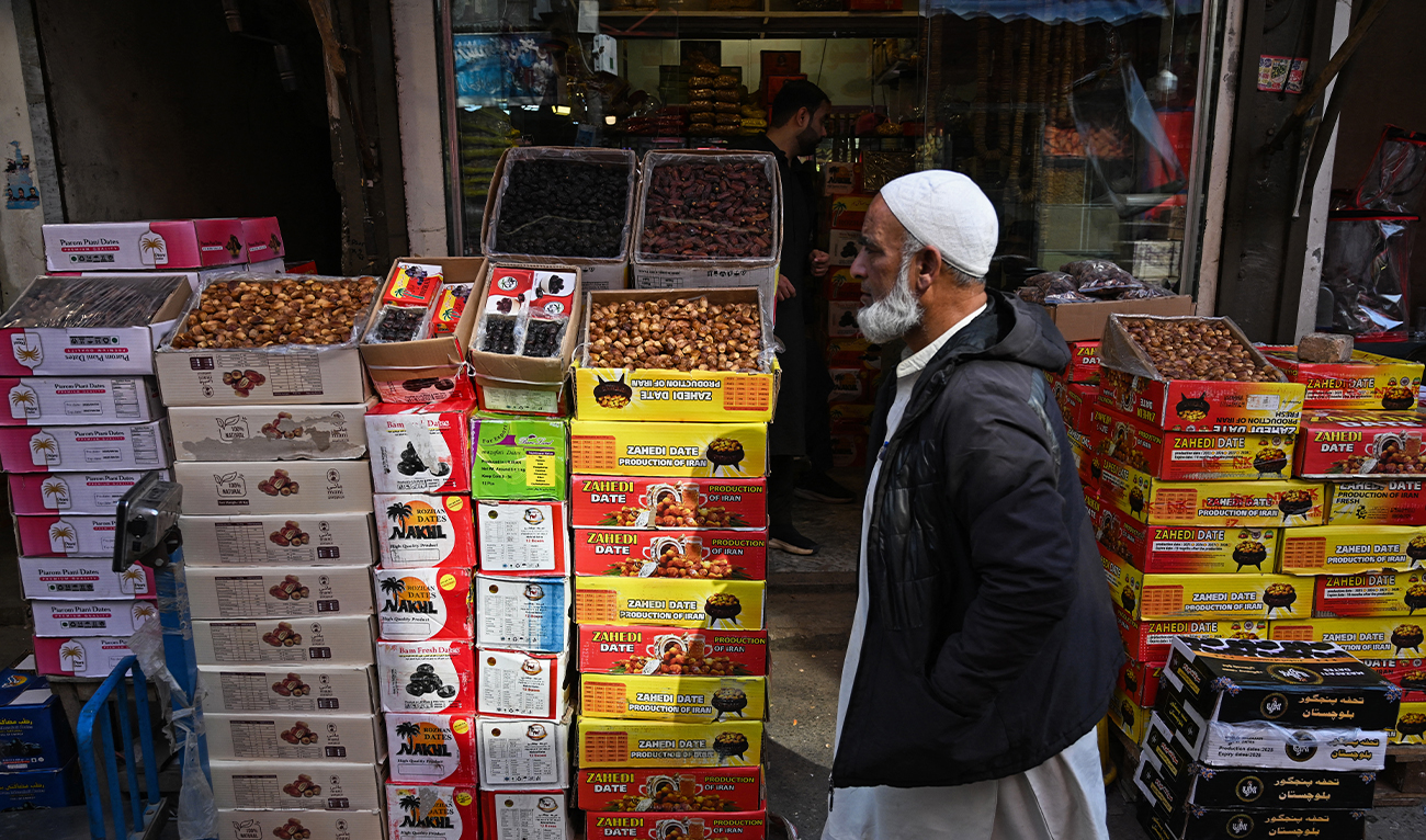 A man walks past cartons of dates, displayed for sale outside a shop ahead of the Islamic holy fasting month of Ramadan in Rawalpindi on February 17, 2026. (AFP)