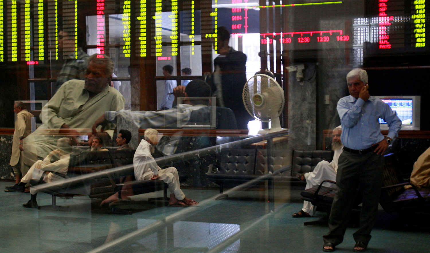 Stockbrokers are seen near an electronic display board during a trading session at the Karachi Stock Exchange in Karahi on November 17, 2008. (REUTERS/File)