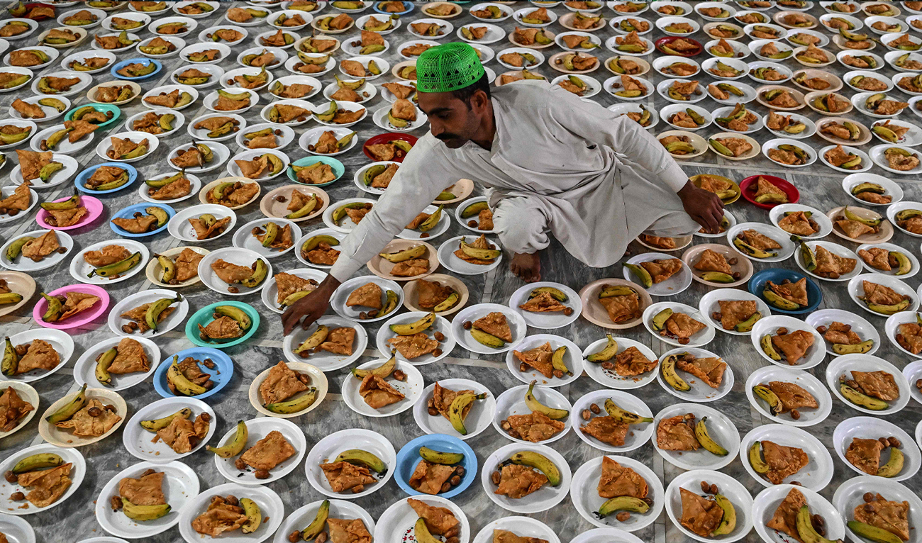 A volunteer prepares the plates of Iftar food on the first day of the Islamic holy month of Ramadan at the Data Darbar shrine in Lahore on February 19, 2026. (AFP)