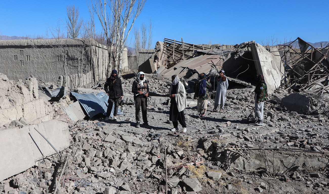 Taliban security personnel stand next to the debris of houses destroyed during an overnight Pakistani airstrike at the Balish village in Urgun district, Paktika Province, on February 22, 2026. (AFP)