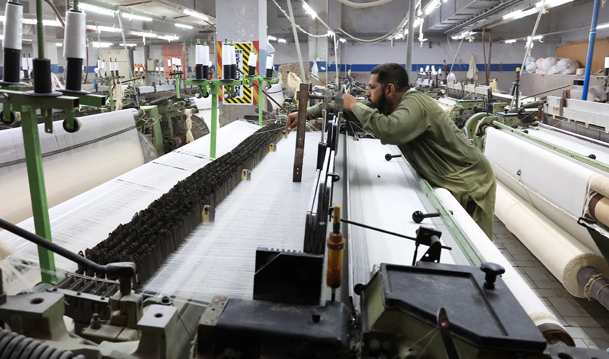 A worker examines cotton yarn threads while working on a loom machine, weaving fabric at a textiles manufacturer in Karachi, Pakistan April 3, 2025. (Reuters/File)