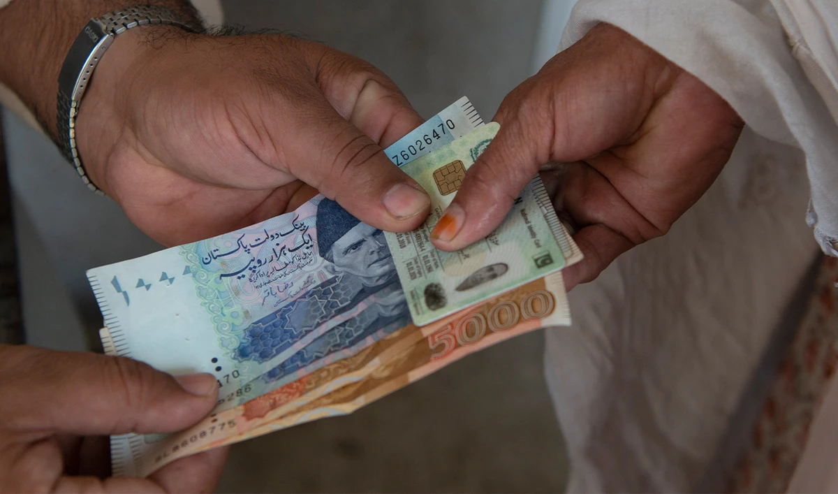 A woman collects emergency cash as part of the Ehsaas Emergency Cash programme for families in need, ahead of the Holy month of Ramadan in Peshawar on April 12, 2021. (AFP/File)