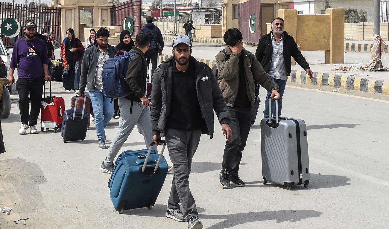 Pakistani nationals walk across the Taftan border after returning from Iran, in Balochistan province, on March 2, 2026 amid ongoing US-Israel strikes on Iran. (AFP)