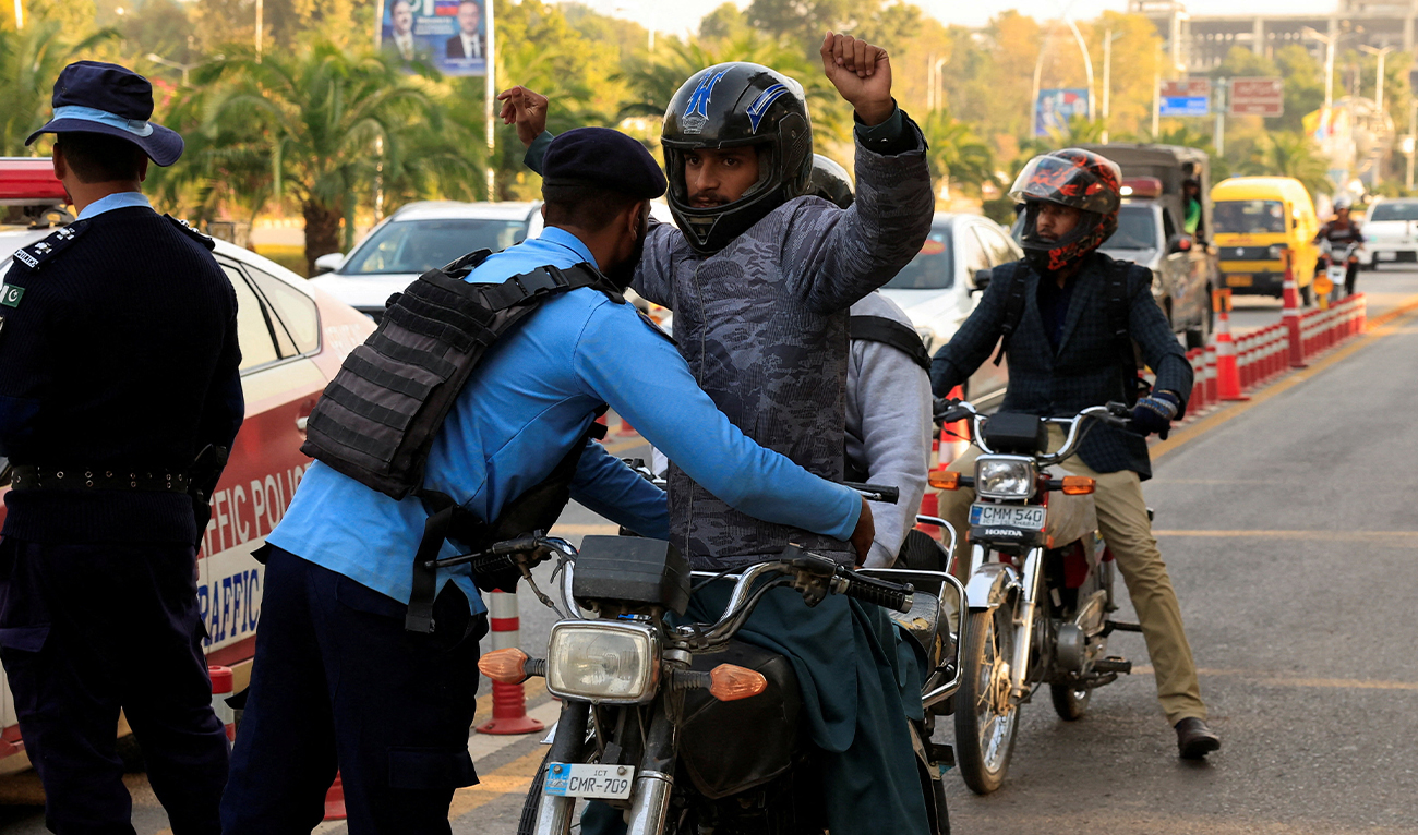 A police officer frisks a biker at a security check post along a road in Islamabad, Pakistan, on November 12, 2025. (Reuters/File)