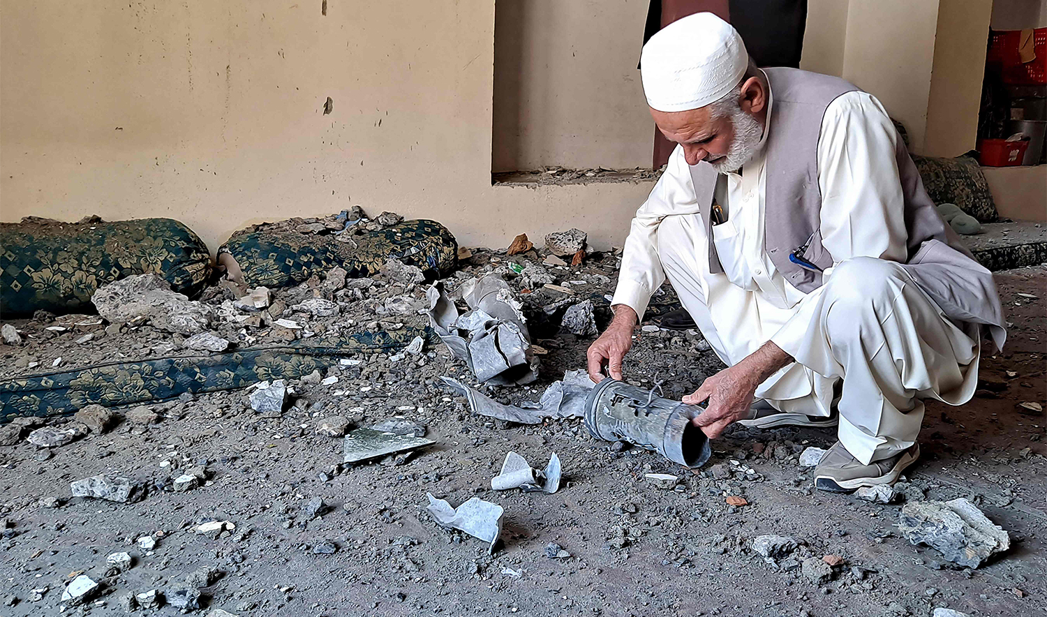 A resident collects fragments of a mortar shell inside his house damaged by cross-border firing at Khyber district, near the frontier province of Khyber Pakhtunkhwa on March 5, 2026 amid the Pakistan-Afghanistan conflict. (AFP/File)