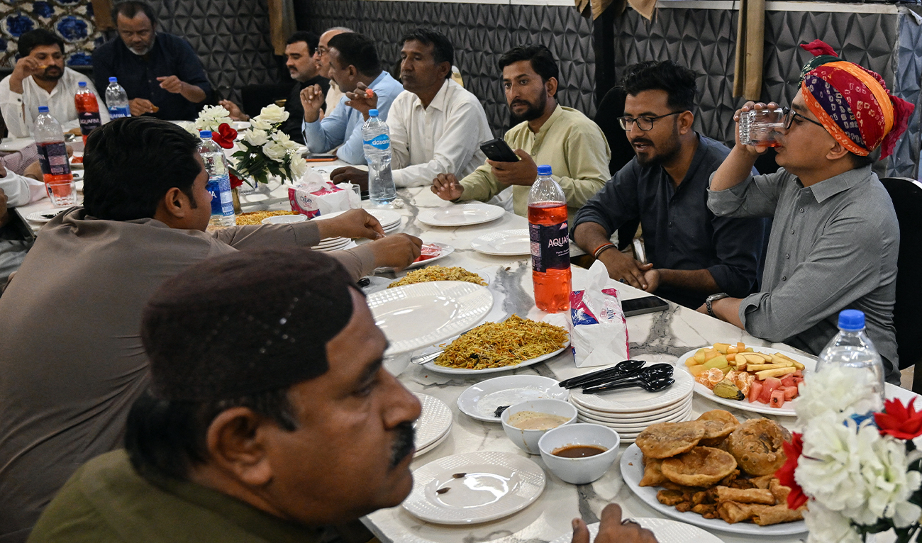 The photograph taken on February 27, 2026, shows Muslim men enjoying a meal as they break their fast with Hindu community during the Islamic holy fasting month of Ramadan, at Mithi in the Tharparkar district of Sindh province, Pakistan. (AFP)