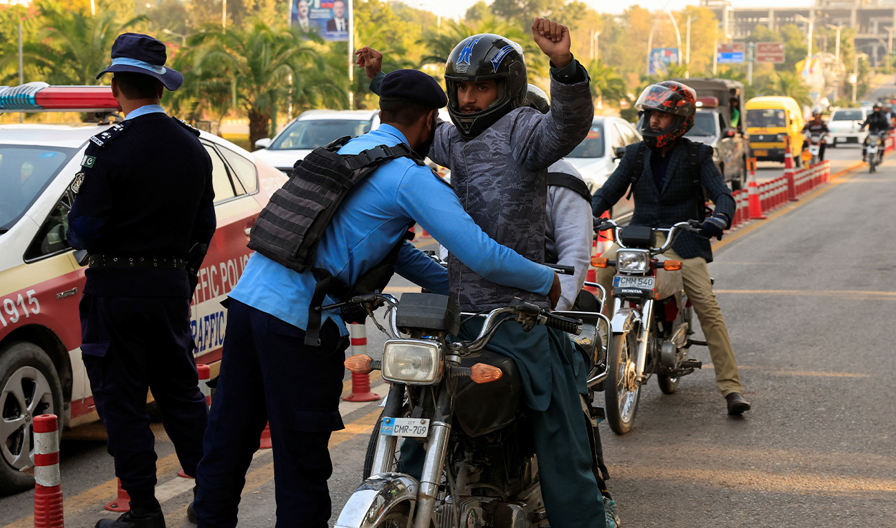 A police officer frisks a biker at a security check post along a road in Islamabad, Pakistan, on November 12, 2025. (Reuters/File)