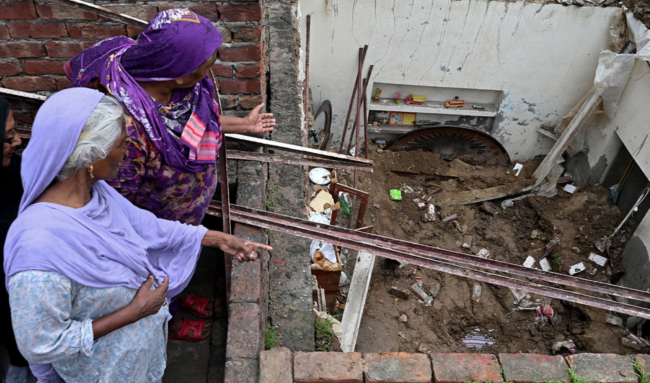 Neighbours look at the collapsed roof of a house owing to heavy monsoon rains in Lahore on July 16, 2025. (AFP/File)