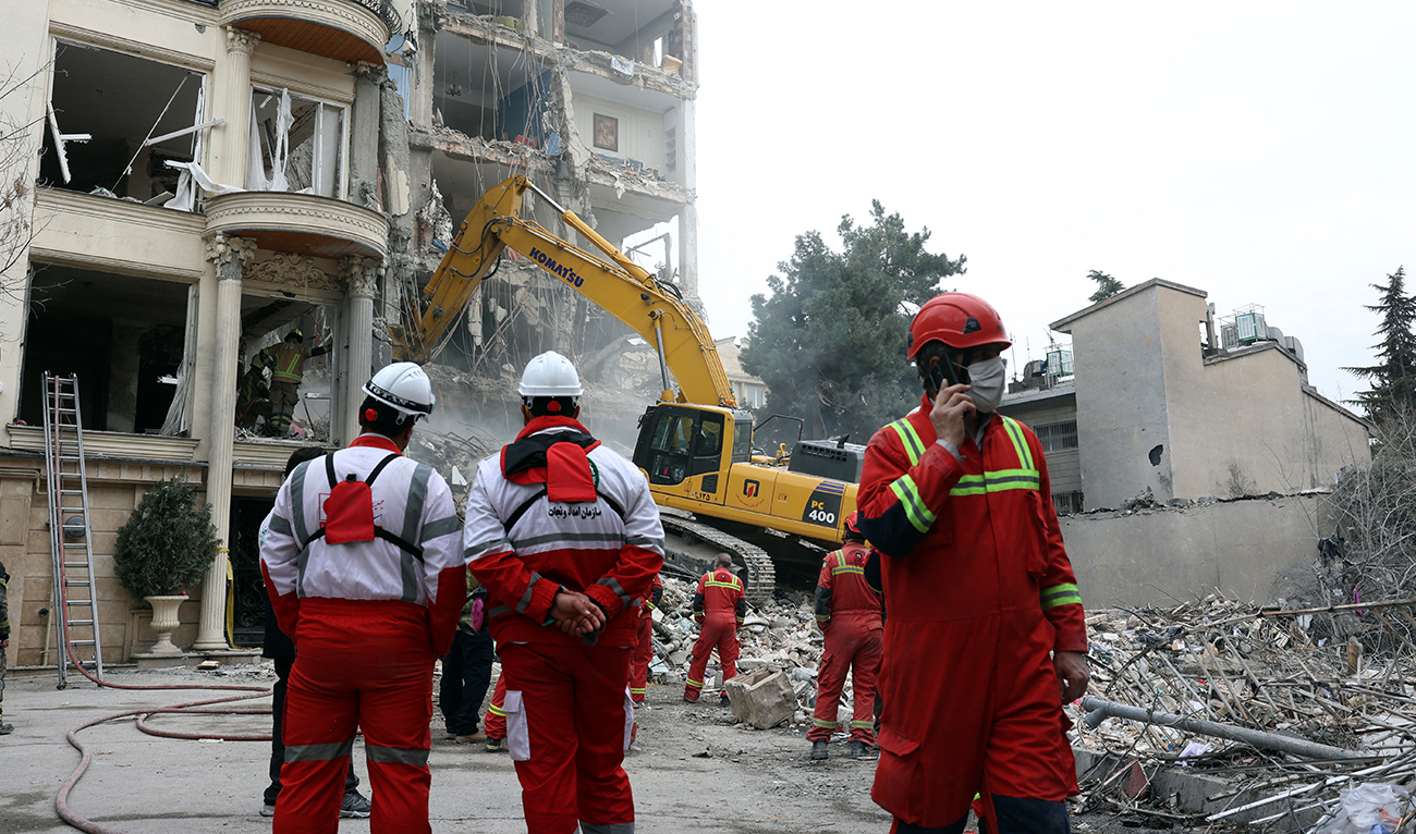Iranian firefighters with the help of an excavator clear rubble from a destroyed residential building in northern Tehran, Iran, on March 23, 2026. (AFP)
