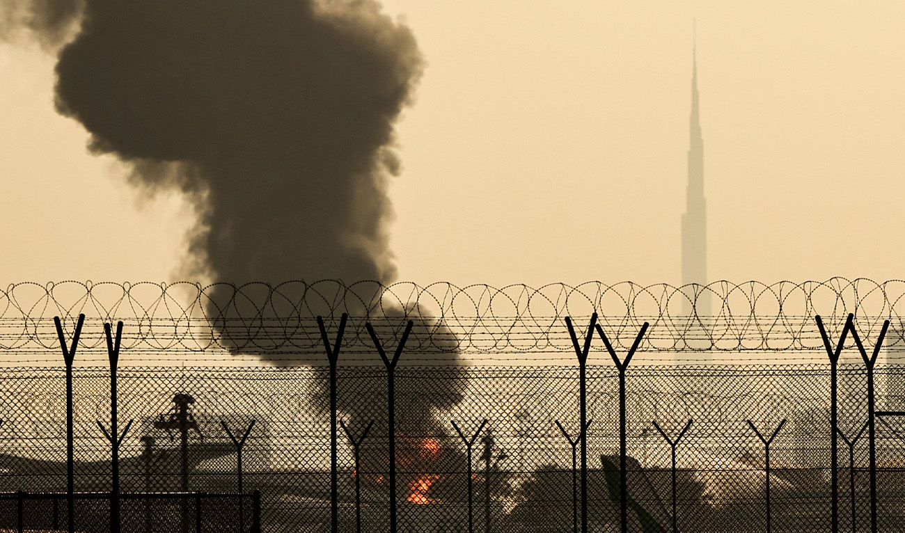 The Dubai skyline with the landmark Burj Khalifa skyscraper (R) is pictured as a smoke plume rises from an ongoing fire near Dubai International Airport on March 16, 2026. (AFP/File)
