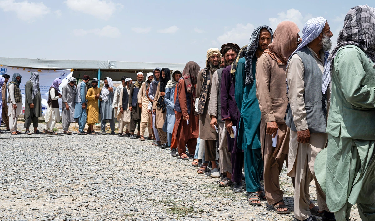 Afghan internally displaced refugee men stand in a queue to identify themselves and get cash as they return home to the east, at the United Nations High Commissioner for Refugees (UNHCR) camp in the outskirts of Kabul on July 28, 2022. (AFP/File)