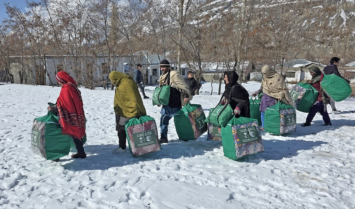 The picture shared by KSrelief onn March 5, 2026, shows people carrying winter kits in northwest Pakistan. (KSrelief)