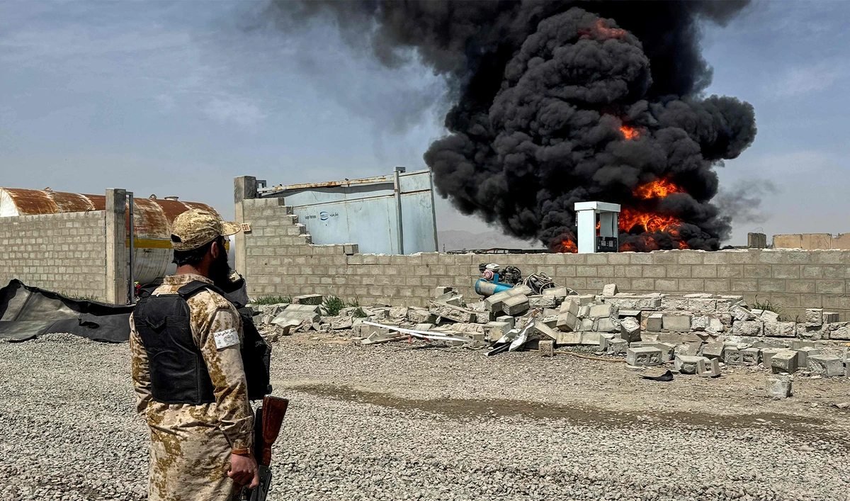 A Taliban security personnel stands as smoke rises from the site after overnight Pakistani airstrikes hit oil depots for commercial airlines, near the Kandahar airport in the Daman district of Kandahar province on March 13, 2026. (AFP)