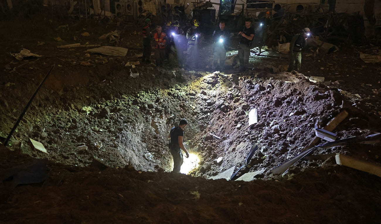 Israeli security forces and first responders inspect the site of an Iranian strike that hit a residential neighbourhood in Petah Tikva on April 2, 2026. (AFP)
