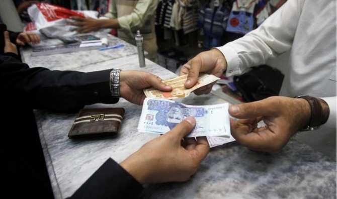 Men exchange Pakistani banknotes at a shop counter in Peshawar, Pakistan November 17, 2017. (Reuters/File)