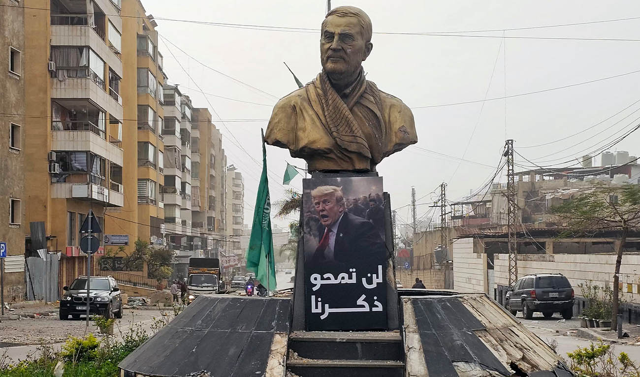 A sign depicting US President Donald Trump, with the caption "you will not erase our memory" in Arabic, is displayed before a memorial depicting Qassem Soleimani, the slain commander of the "Quds Force" of Iran's Islamic Revolutionary Guards Corps (IRGC) who was killed by a US airstrike in 2020, along the road leading to Beirut International Airport in Beirut on April 4, 2026. (AFP)
