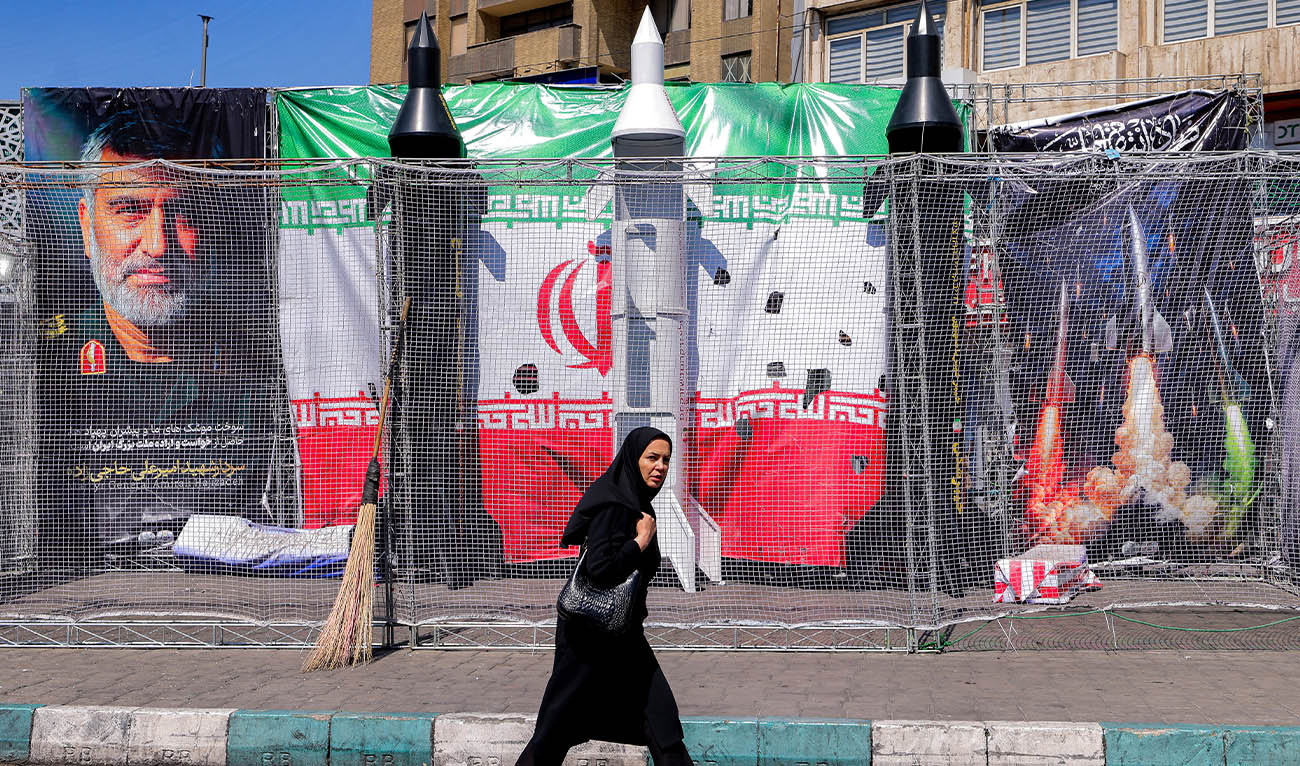 A woman walks past mockups of Iranian missiles along Valiasr Square in Tehran on April 6, 2026. (AFP)