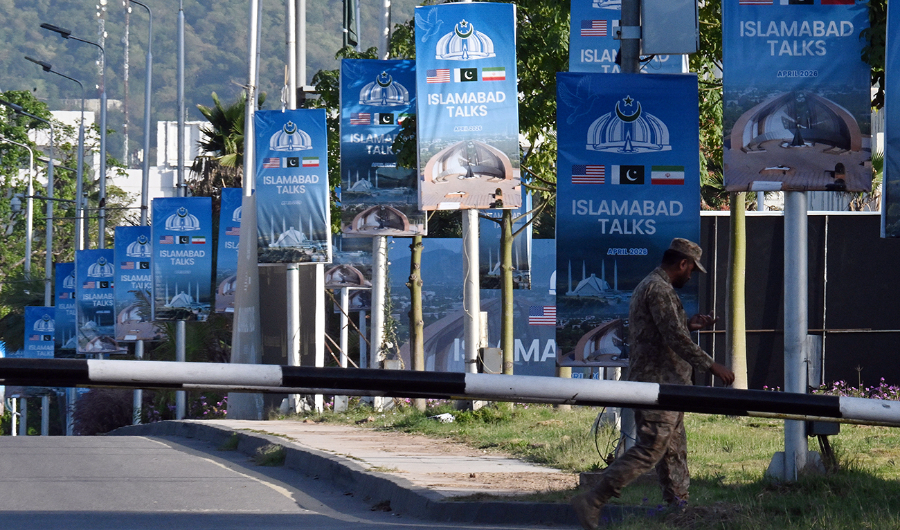 An army soldier walks past posters highlighting Pakistan’s mediation of Iran–US peace talks near the Serena Hotel at the Red Zone area in Islamabad on April 22, 2026. (AFP)