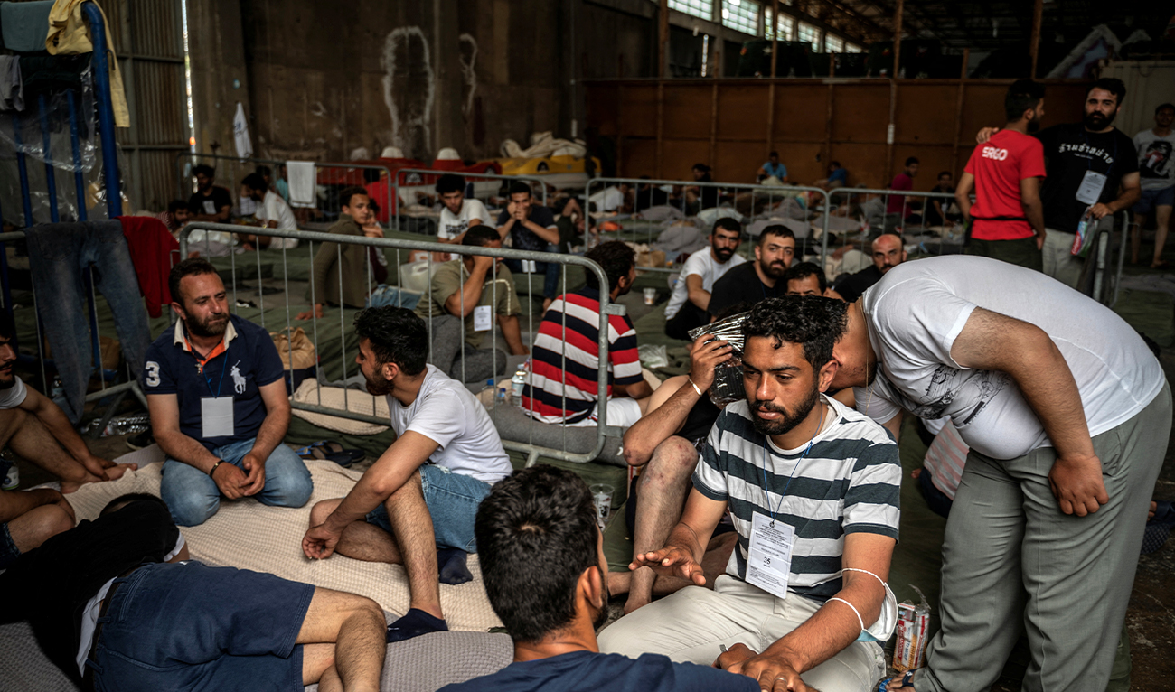Migrants who were rescued at sea off Greece after their boat capsized are seen inside a warehouse, used as shelter, at the port of Kalamata, Greece, on June 15, 2023. (Reuters/File)