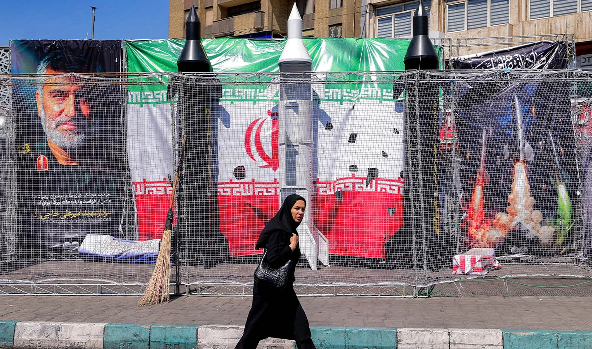 A woman walks past mockups of Iranian missiles along Valiasr Square in Tehran on April 6, 2026. (AFP)