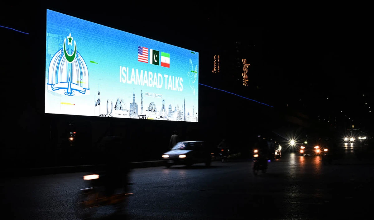Commuters ride past a digital screen as the US and Iran hold peace talks in Islamabad on April 11, 2026. (AFP)