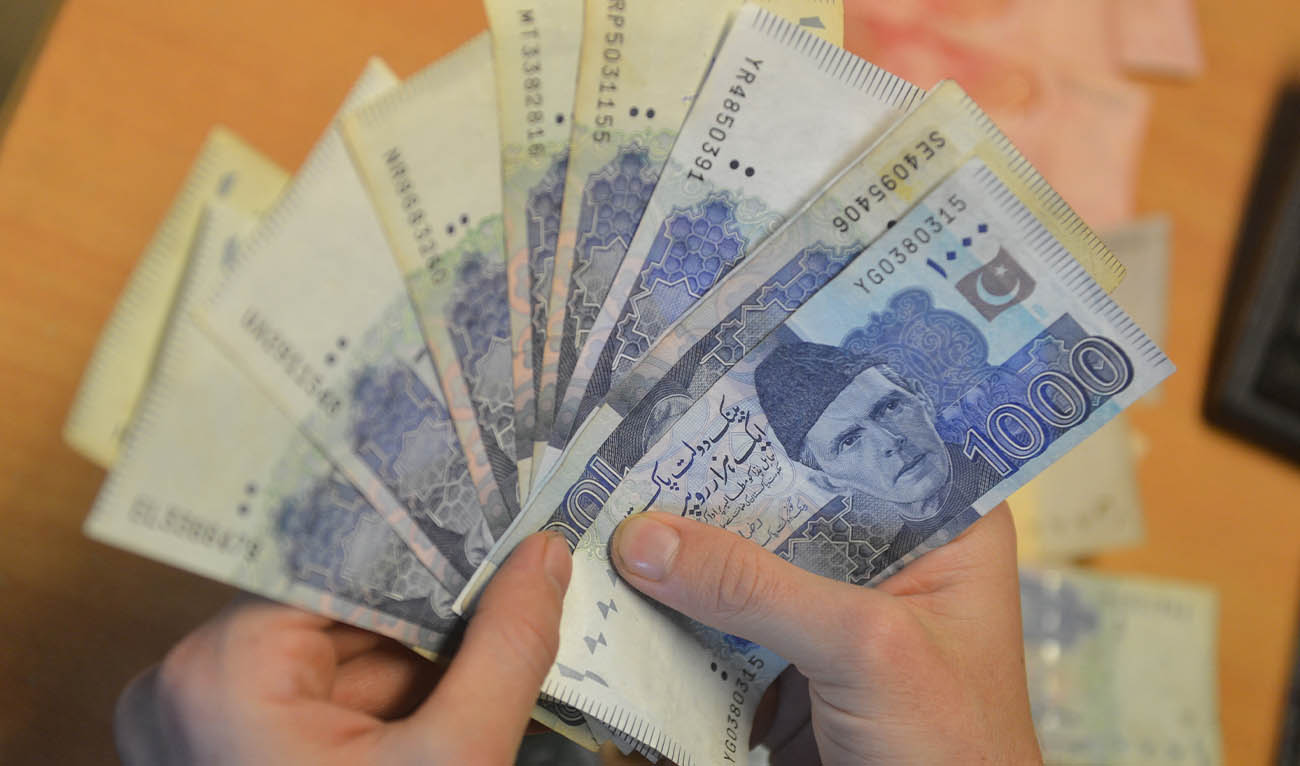 A money changer counts Pakistan's currency at a market in Karachi on January 6, 2023. (AFP/ file)