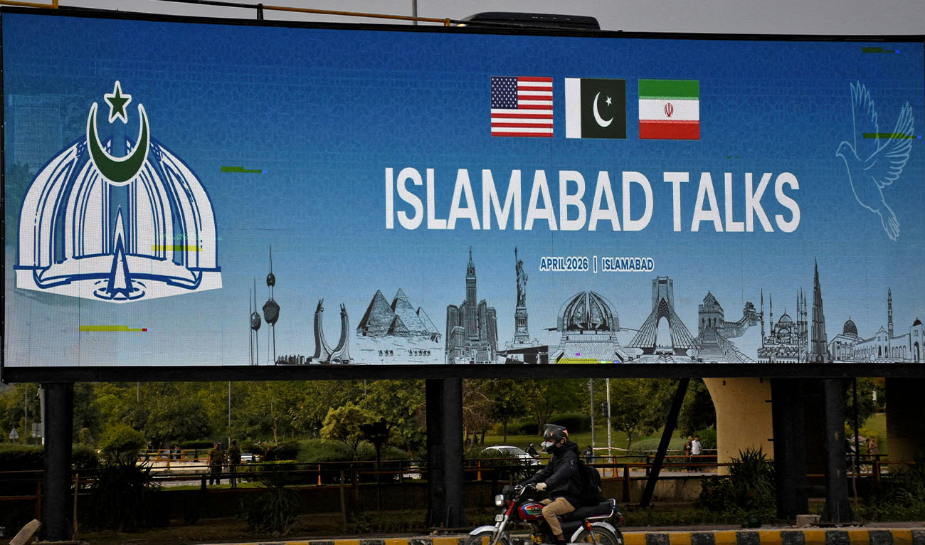 A man rides his motorbike past a billboard installed alongside a road as Pakistan prepares to host the US and Iran for peace talks, in Islamabad, Pakistan, on April 10, 2026. (Reuters/File)
