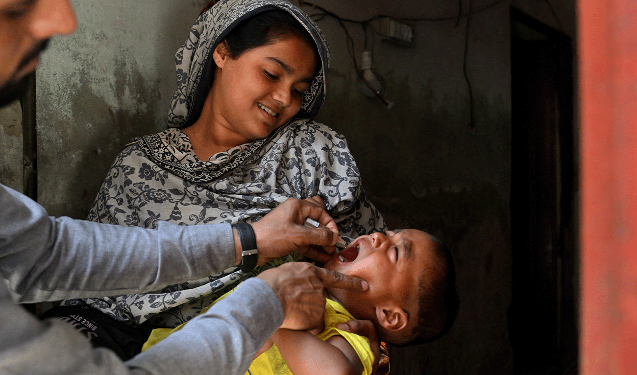 A healthcare worker administers polio drops to a child for vaccination during a door-to-door poliovirus eradication campaign in Lahore on May 19, 2026. (AFP/File)