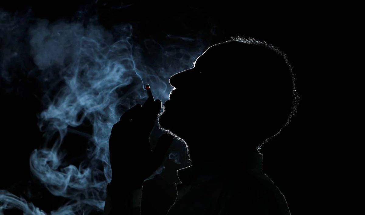 A man is seen in silhouette as he smokes a cigarette at his shop in Peshawar, Pakistan May 28, 2019. (REUTERS)