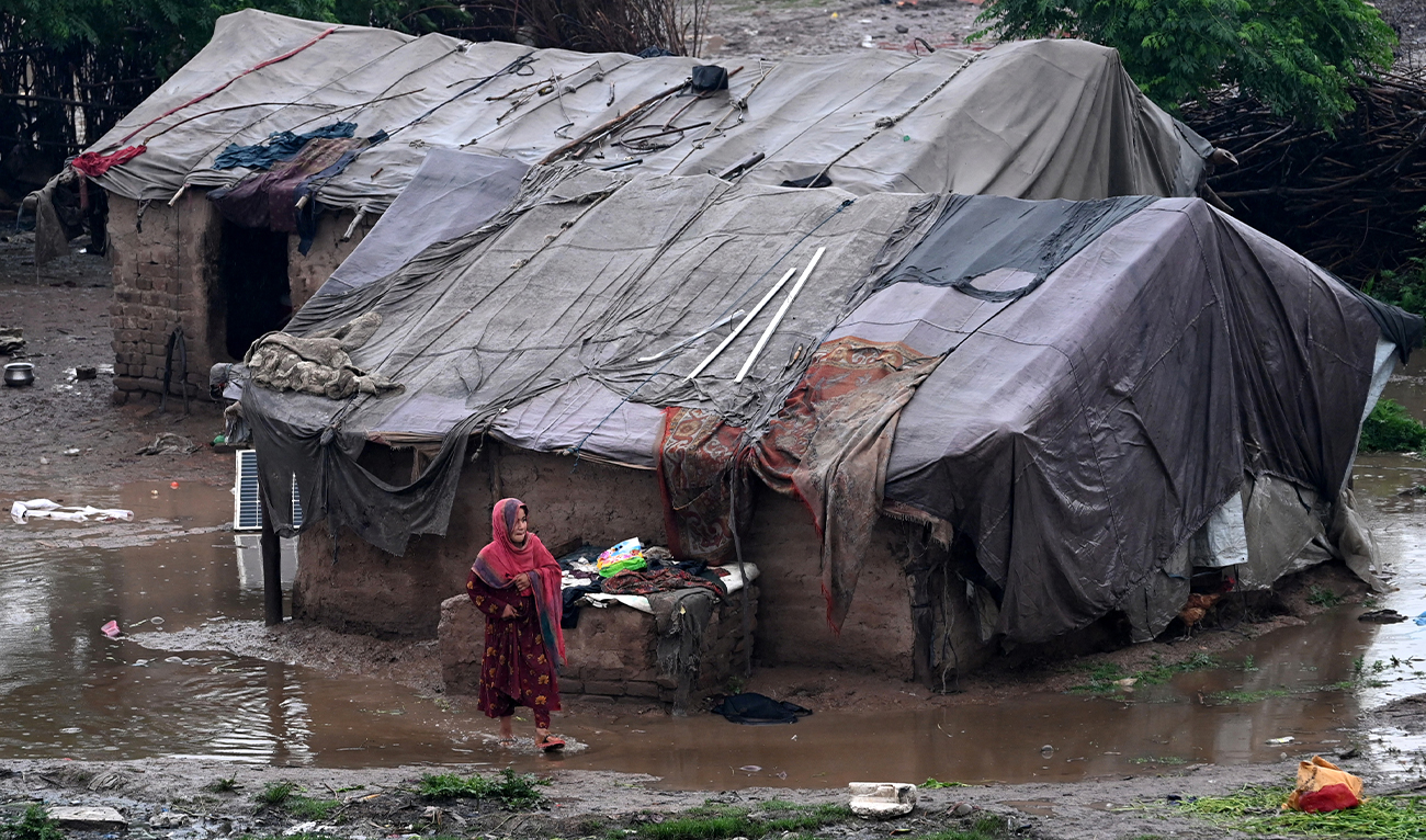 A girl walks through a pool of water near makeshift shelters after heavy rainfall in Peshawar, Pakistan, on April 3, 2026. (AFP/File)