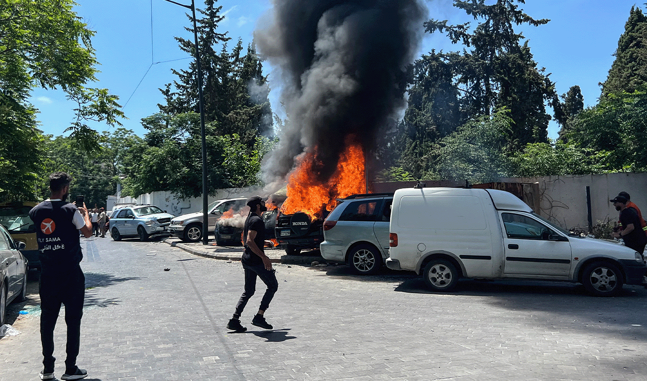 A man takes pictures of burning vehicles as first responders rush to the scene after an Israeli airstrike that hit a car in Sidon, Lebanon on June 10, 2026. (AFP)