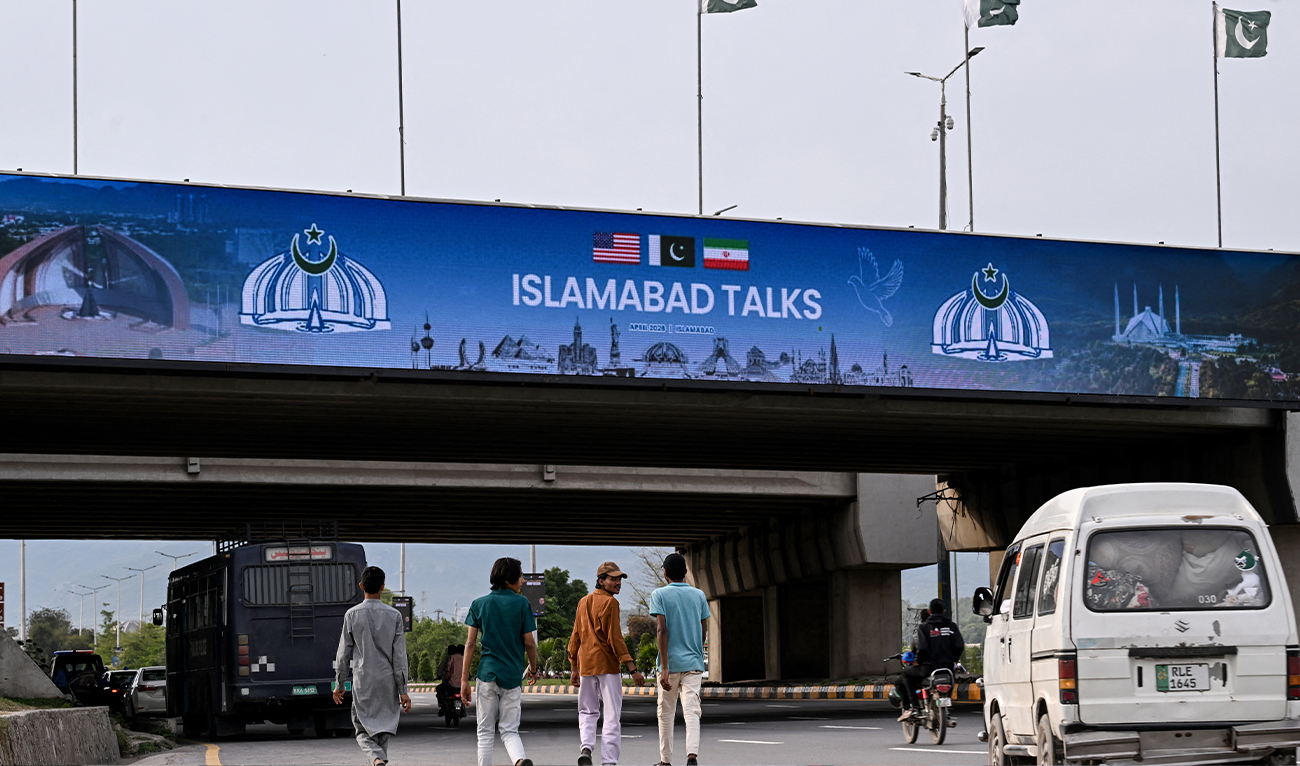 Boys walk under a digital screen displaying news of US-Iran peace talks along a road in Islamabad, Pakistan, on April 10, 2026. (AFP/File)