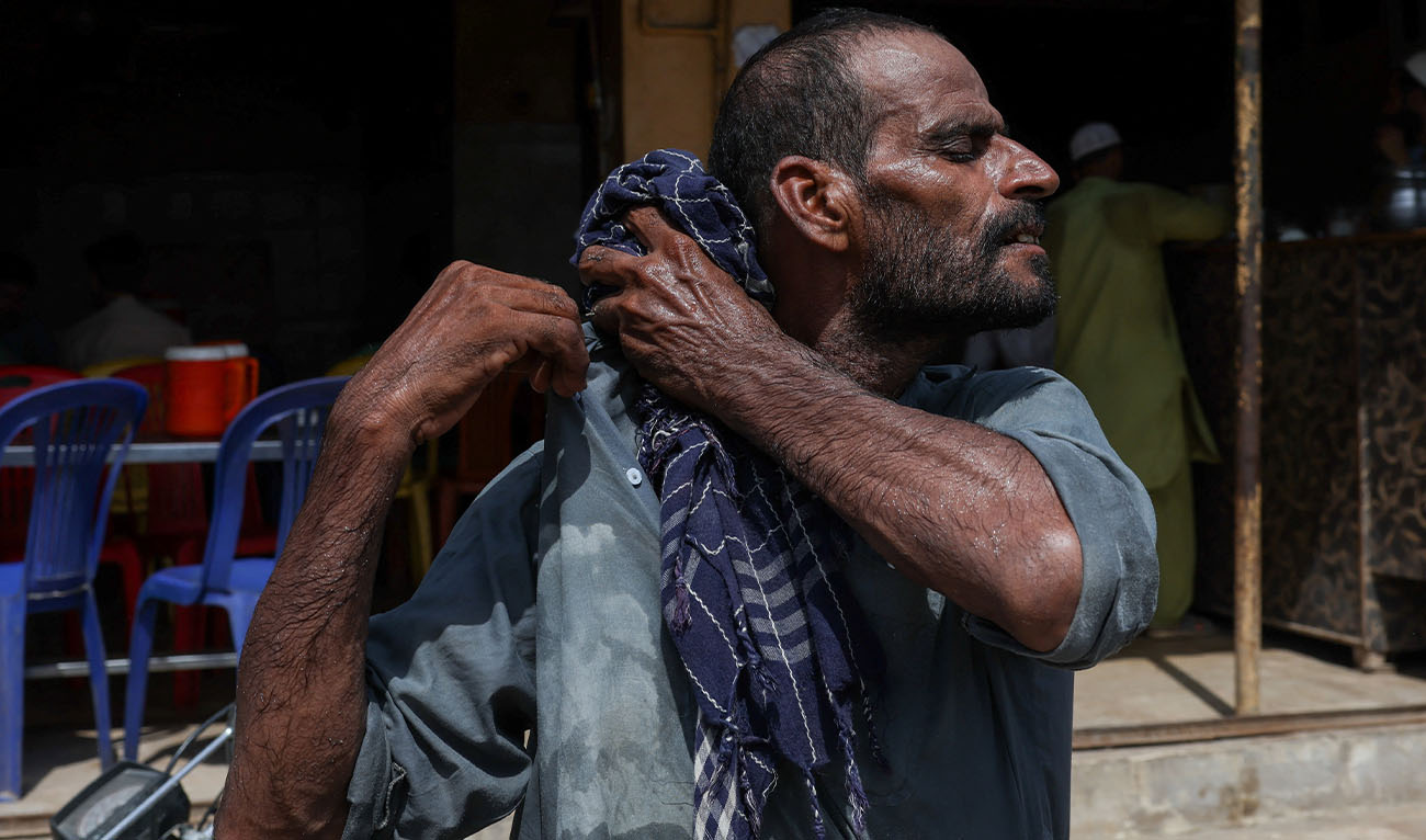 Allah Bux, 30, a labourer, wipes sweat with his scarf after offloading supplies outside a cafe during a scorching summer day in Karachi, Pakistan. June 11, 2026. (Reuters/File)